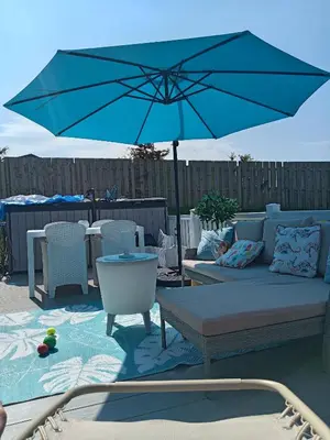 a patio with a couch and a blue umbrella at Newquay Bay Resort - Poppy's Lodge Retreat in Newquay