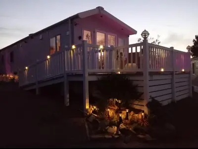 a house with a deck with lights on it at Newquay Bay Resort - Poppy's Lodge Retreat in Newquay