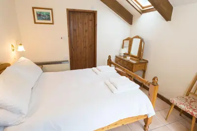 a bedroom with a white bed with towels on it at Lower Mulberry Cottage in Bodmin