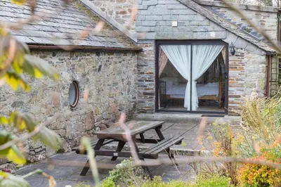 a picnic table in front of a stone building with a window at Lower Mulberry Cottage in Bodmin