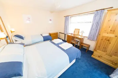 two beds in a room with a table and a desk at Lower Mulberry Cottage in Bodmin