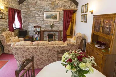 a living room with a couch and a table with flowers at Lower Mulberry Cottage in Bodmin