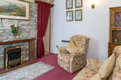 a living room with a chair and a fireplace at Lower Mulberry Cottage in Bodmin
