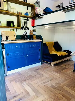 a kitchen with blue cabinets and a wooden floor at Hillhead Hideaway in Saint Columb Major