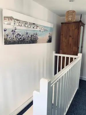 a room with a white crib and a painting on the wall at Holm Cottage near Charlestown in St Austell