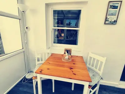 a wooden table and chairs in a room with a window at Holm Cottage near Charlestown in St Austell