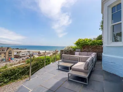 a patio with a couch and a view of the ocean at Harbour House in Looe