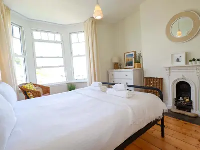 a bedroom with a white bed and a fireplace at Harbour House in Looe