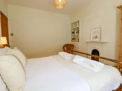 a white bed in a room with a fireplace at Harbour House in Looe