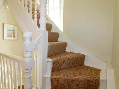 a stairway with white railings and a brown seat at Harbour House in Looe