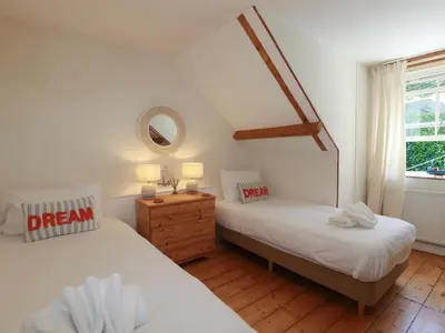 two twin beds in a room with a window at Harbour House in Looe