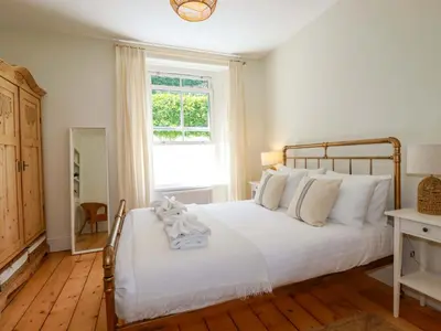 a bedroom with a bed with white sheets and a window at Harbour House in Looe