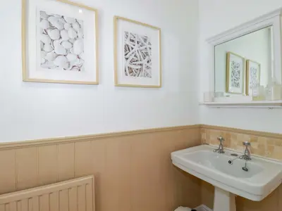a bathroom with a sink and two pictures on the wall at Harbour House in Looe