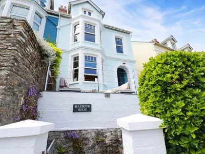 a white house with a sign in front of it at Harbour House in Looe
