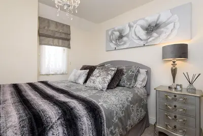 a bedroom with a bed and a lamp and a dresser at Dolls Cottage in Looe
