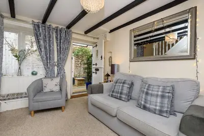 a living room with a couch and a chair and a mirror at Dolls Cottage in Looe