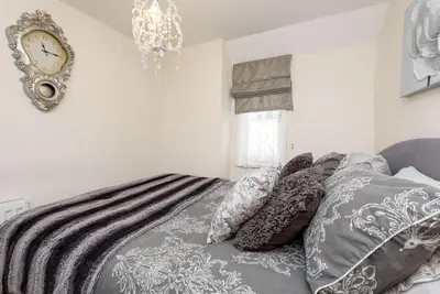 a bed with pillows and a clock on the wall at Dolls Cottage in Looe