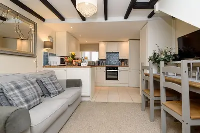 a living room and kitchen with a couch and a table at Dolls Cottage in Looe