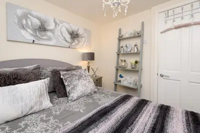 a bedroom with a bed and a chandelier at Dolls Cottage in Looe