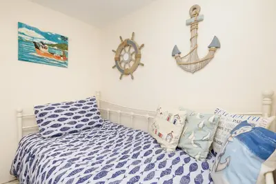 a bedroom with a bed and a nautical sign on the wall at Dolls Cottage in Looe