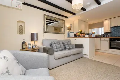 a living room with a couch and a kitchen at Dolls Cottage in Looe