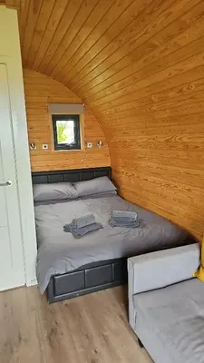 two beds in a room with a wooden ceiling at Glamping Pod in Mawgan Porth