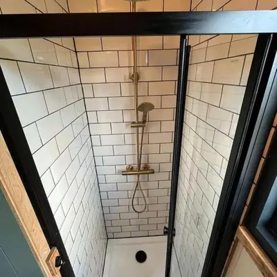 a shower with a shower head in a bathroom at Shepherds Hut in Mawgan Porth