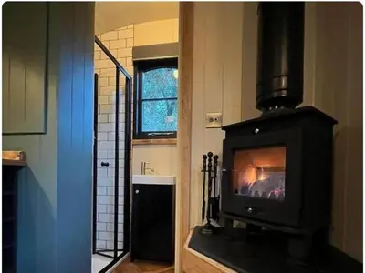 a fireplace in a kitchen with a stove at Shepherds Hut in Mawgan Porth