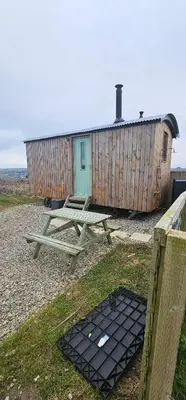 a picnic table in front of a wooden building at Shepherds Hut in Mawgan Porth