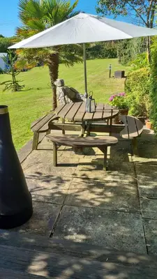 a wooden picnic table with a white umbrella at The Cabin in St Austell