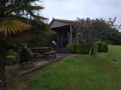 a small house with a statue in the yard at The Cabin in St Austell