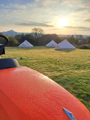 a group of tents in a field with the setting sun at The Cabin in St Austell