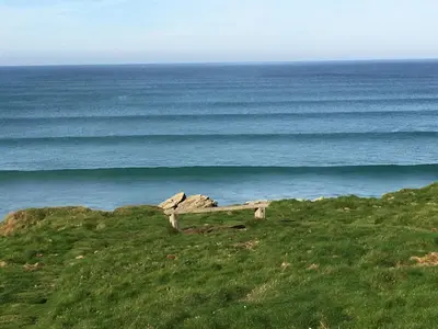 a bench on a hill overlooking the ocean at Glendorgal Sands - The best sea views in Cornwall in Saint Columb Minor