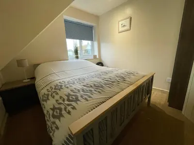 a large bed in a bedroom with a window at Glendorgal Sands - The best sea views in Cornwall in Saint Columb Minor