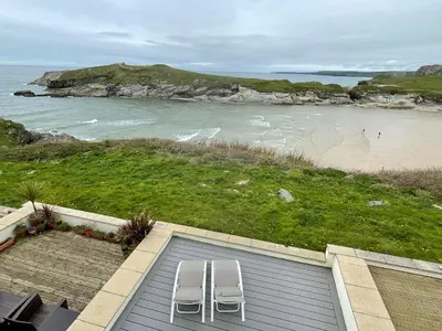 two white chairs sitting on top of a building next to a beach at Glendorgal Sands - The best sea views in Cornwall in Saint Columb Minor