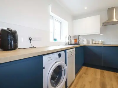 a kitchen with a washing machine and blue cabinets at Folly View in Redruth