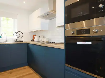 a kitchen with blue cabinets and a black oven at Folly View in Redruth