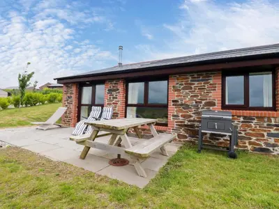 a picnic table and chairs in front of a brick house at Folly View in Redruth