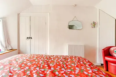 a bedroom with a bed with a red chair at Captains Ground in Altarnun
