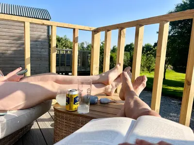 two people laying on a deck reading a book at Morthana Shepherd Hut in Scorrier
