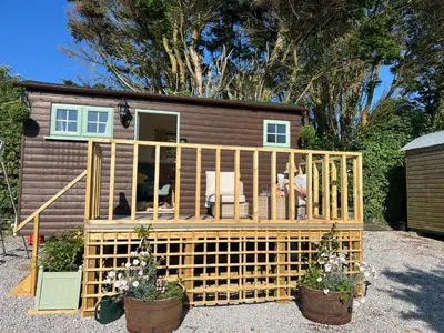 a tiny house with a deck in a yard at Morthana Shepherd Hut in Scorrier