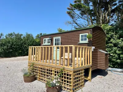 a tiny house with a porch and a deck at Morthana Shepherd Hut in Scorrier