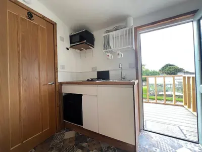 a kitchen with a counter and a door to a balcony at Morthana Shepherd Hut in Scorrier