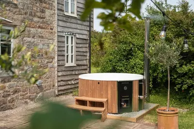 a bath tub sitting outside of a house at Naut Retreat - Idyllic hideaway with hot tub, gym & gamesroom ideally located in Zennor near St Ives in Penzance