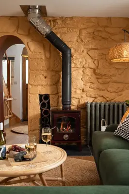 a living room with a fireplace and a table with wine glasses at Naut Retreat - Idyllic hideaway with hot tub, gym & gamesroom ideally located in Zennor near St Ives in Penzance