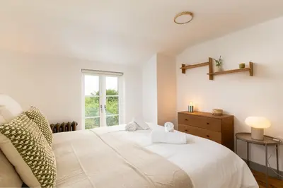a bedroom with a white bed and a window at Naut Retreat - Idyllic hideaway with hot tub, gym & gamesroom ideally located in Zennor near St Ives in Penzance