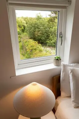 a lamp sitting next to a window in a room at Naut Retreat - Idyllic hideaway with hot tub, gym & gamesroom ideally located in Zennor near St Ives in Penzance