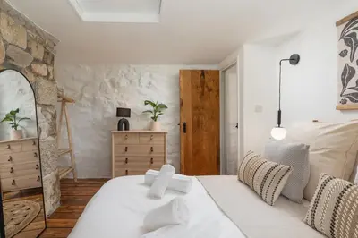 a bedroom with a white bed and a stone wall at Naut Retreat - Idyllic hideaway with hot tub, gym & gamesroom ideally located in Zennor near St Ives in Penzance