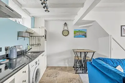 a kitchen with white cabinets and a blue couch at Finest Retreats - Farleigh Cottage in Looe