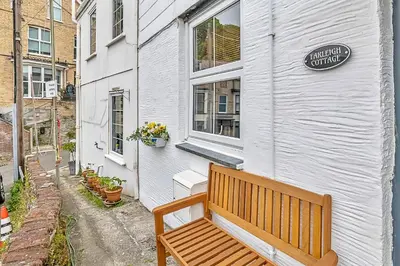 a wooden bench sitting outside of a white building at Finest Retreats - Farleigh Cottage in Looe